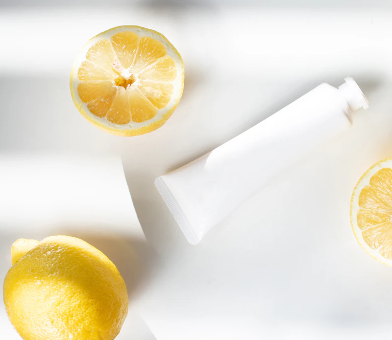 Tubo de crema blanco sin etiqueta junto a limones cortados