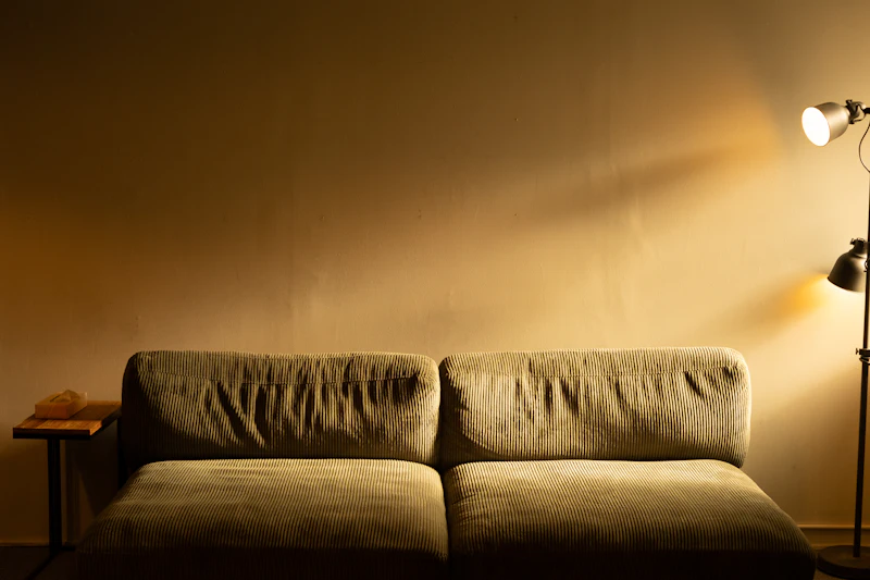 Salón con sofá de pana iluminado por una lámpara de pie de luz cálida