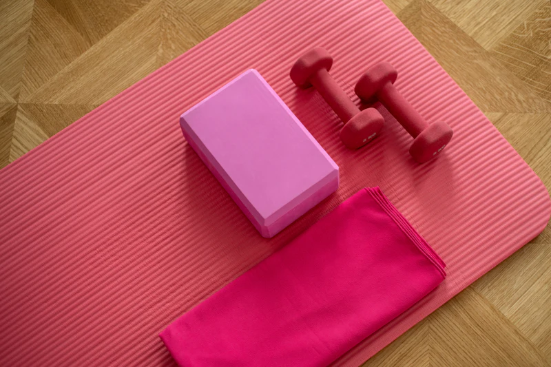 Esterilla rosa con mancuernas y un bloque de yoga