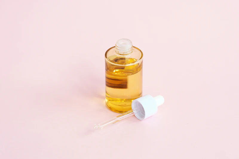Frasco de sérum de cristal con cuentagotas sobre fondo rosa