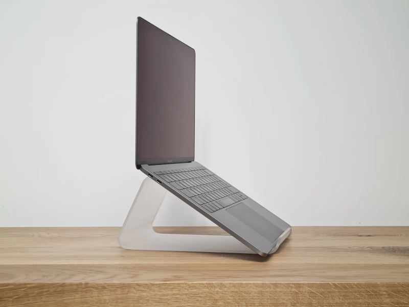Portátil sobre un soporte de aluminio en una mesa de madera