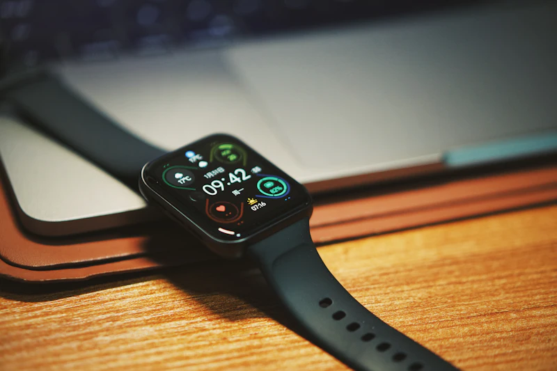 Reloj inteligente apoyado sobre un portátil en una mesa de madera